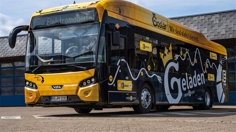 Gelb-schwarzer Elektrobus mit der Aufschrift 'Goslar Wir sind elektrisch' und 'Geladen' steht vor einem Gebäude