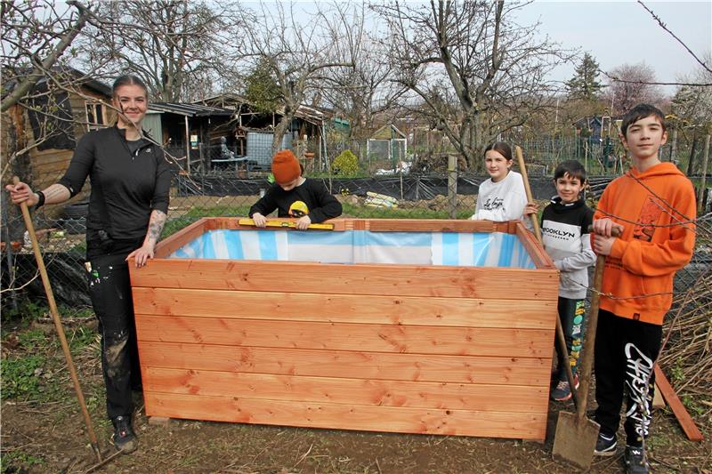 Bad Harzburg: Ein Dschungel im Schrebergarten Gemeinsam mit FSJlerin Merle stehen die Kinder vor ihrem selbstgebauten Meisterwerk: in das Hochbeet sollen künftig Gemüsepflanzen und Kräuter wandern. Vorher kommt jedoch Strauchschnitt, Kompost und Erde hinein. Foto: Jenzora