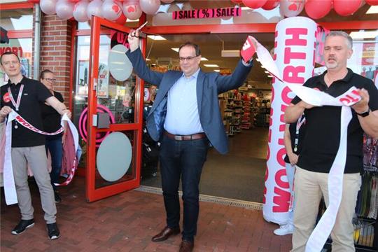 Gerahmt von Filialleiter Sebastian Koblitz (links) und Bezirksleiter Alexander Petersen gibt Bürgermeister Ingo Henze am Donnerstag den Weg zum neuen Woolworth-Store frei.