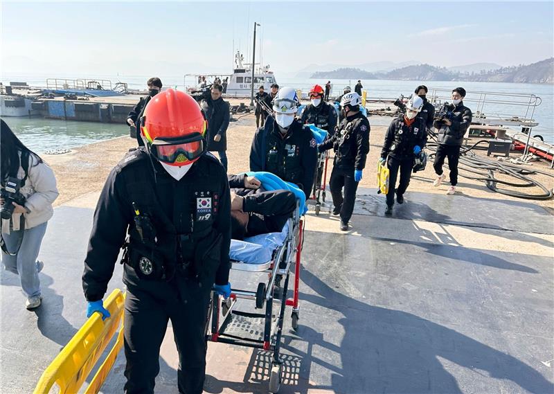 Nach Bootsunglück vor Südkorea neun Menschen vermisst Gerettete Besatzungsmitglieder werden von Rettungskräften auf Bahren getragen, als sie in einem Hafen in Mokpo in Südkorae ankommen.