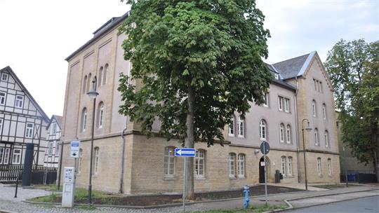 Straßenecke mit altem mehrstöckigem Gebäude, Fachwerkhaus im Hintergrund und großem Baum davor