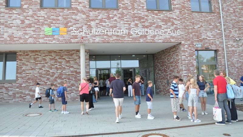 Schülerinnen und Schüler stehen im Sommer vor dem Eingang des riesigen Schulzentrums Goldene Aue.