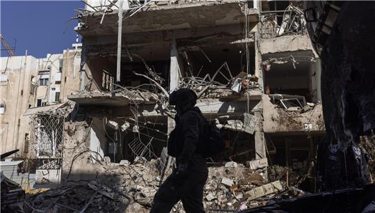 Silhouette einer Person mit Helm vor einem stark beschädigten, teilweise eingestürzten Gebäude