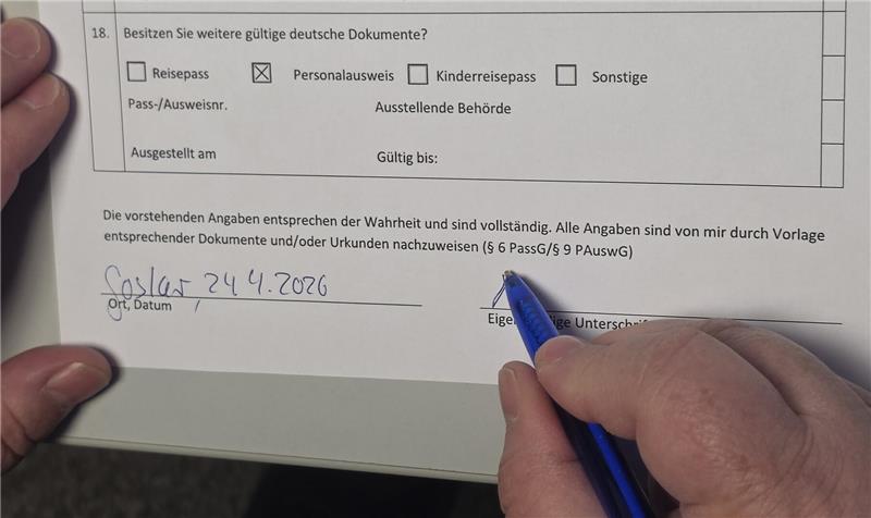 Hand füllt Formular mit Datum 'Goslar 24.4.2026' und Unterschrift aus.