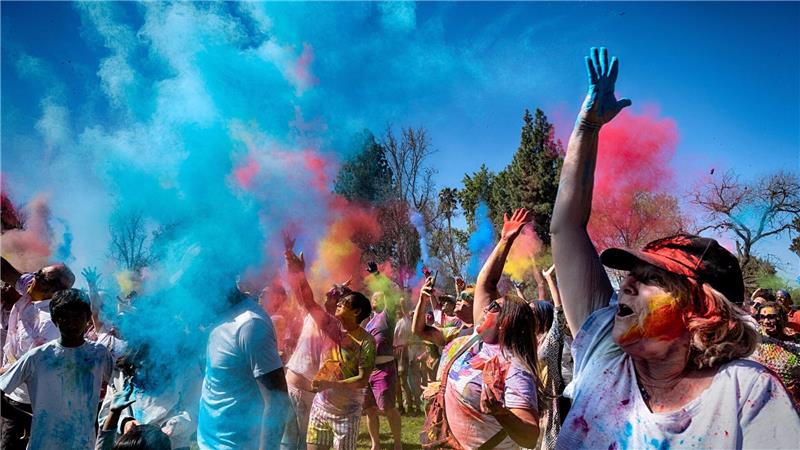 Gläubige jubeln und tanzen, als farbiges Pulver auf sie geworfen wird, um Holi zu feiern.