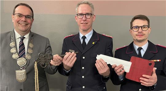 Drei Personen halten zwei symbolische Schlüssel. 