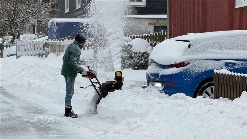 Das Bild zeigt einen Mann, der mit einer Schneefräse auf einen Wagen zufährt.