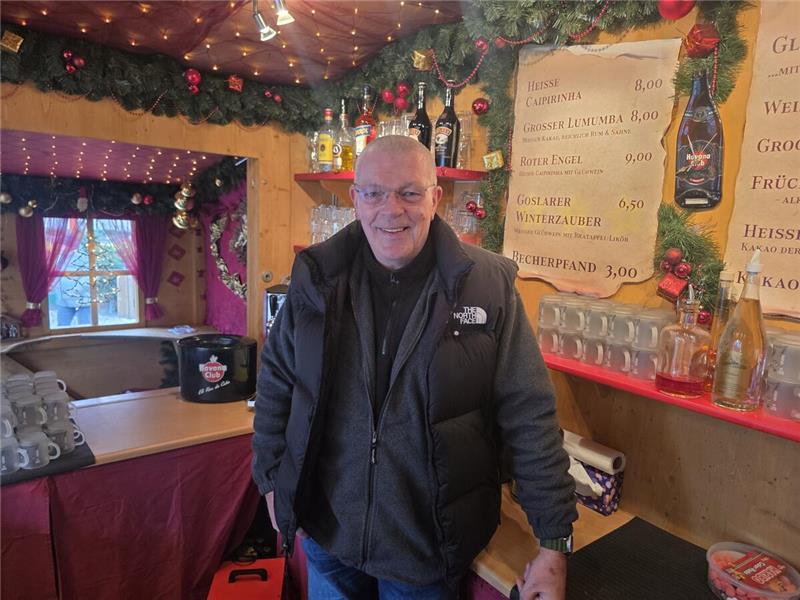 Ein Mann steht in einer weihnachtlich geschmückten Hütte.