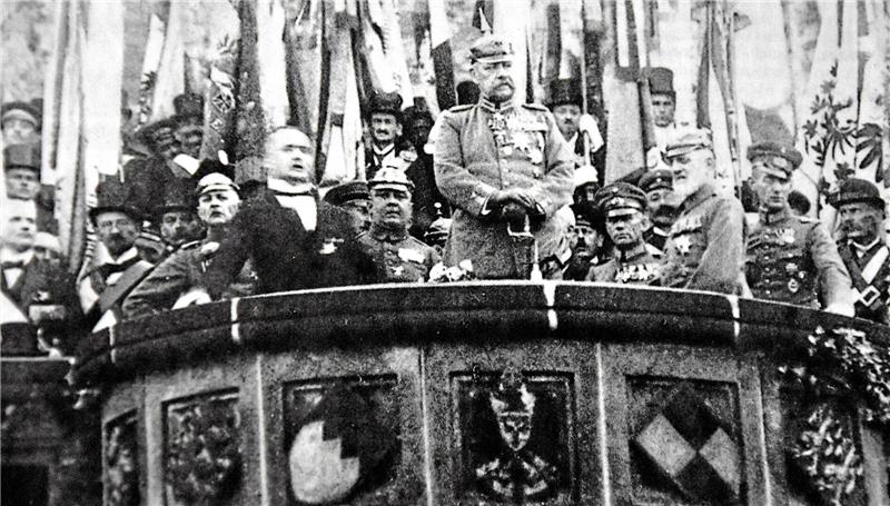 Schwarz-weiß-Fotografie einer Gruppe von Soldaten in Uniform auf einem Balkon mit Wappenverzierungen