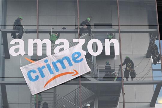 Greenpeace-Aktive hängen während der Rabattaktion Black Friday ein Plakat gegen die Ressourcenverschwendung des Online-Versandhändlers Amazon an dessen Gebäude in München auf.