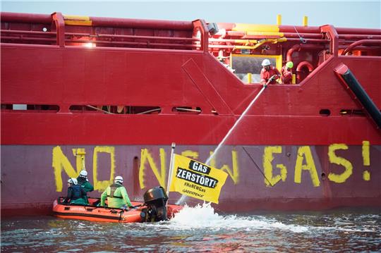 Greenpeace-Aktivisten mit einem Schlauchboot vor einem Schiff im Hafen von Mukran.