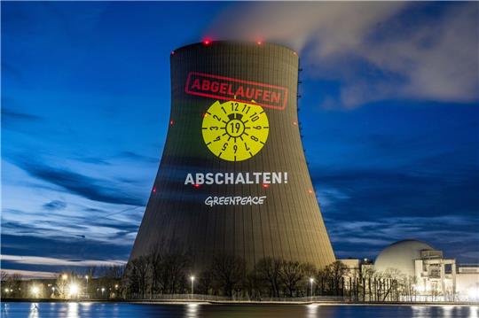 Greenpeace-Aktivisten projizieren eine abgelaufene HU-Plakette auf den Kühlturm am AKW Isar 2.