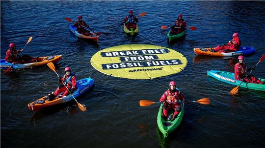 Greenpeace fordert bei einer Aktion am Veranstaltungsort die Abkehr von fossilen Energien.