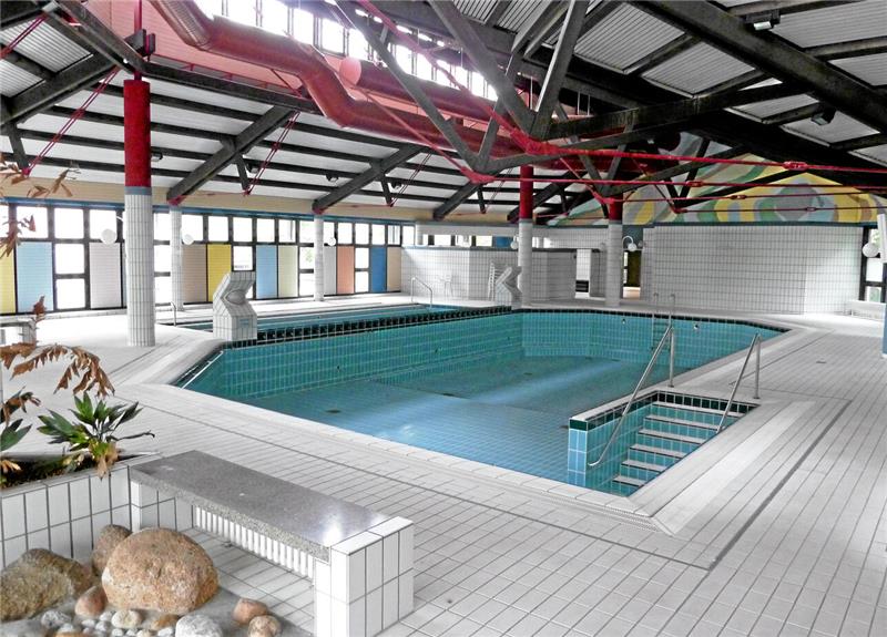 Innenraum eines leeren Schwimmbeckens mit weißen Fliesen und roten Stahlträgern im Dach