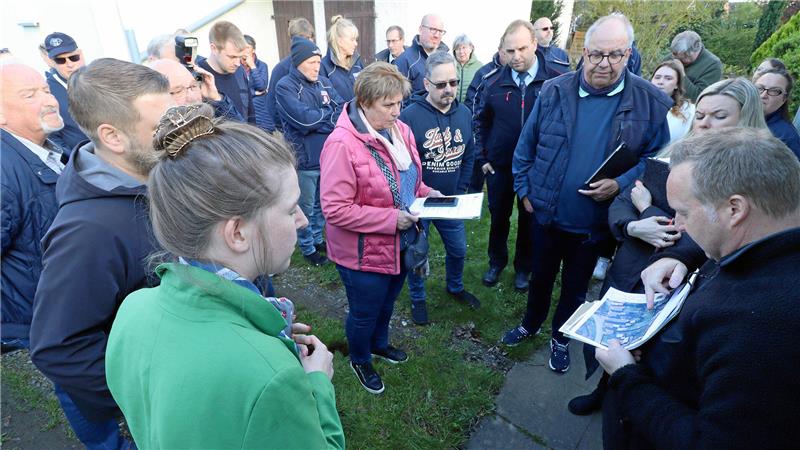 Viele Personen stehen im Halbkreis um einen Mann mit Lageplan.