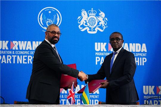 Großbritanniens Innenminister James Cleverly (l) und Vincent Birut, Außenminister von Ruanda, schütteln sich die Hände. Mit dem neuen Vertrag will die britische Regierung Asylsuchende künftig in das ostafrikanische Land abschieben.