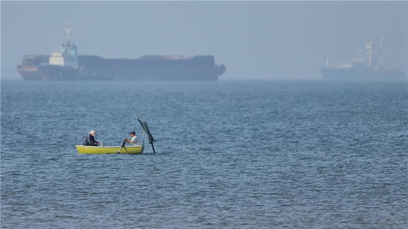 Große Weltlage, kleiner Kahn: Zwei Männer fahren in einem Ruderboot in der Straße von Hormus.