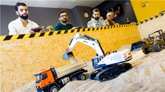 Gründer Siymo Othman (links) steuert mit Freunden kleine Bagger, Radlader und Lastwagen in seinem neu eröffneten Bagger-Café. Es soll das erste dieser Art in Deutschland sein.