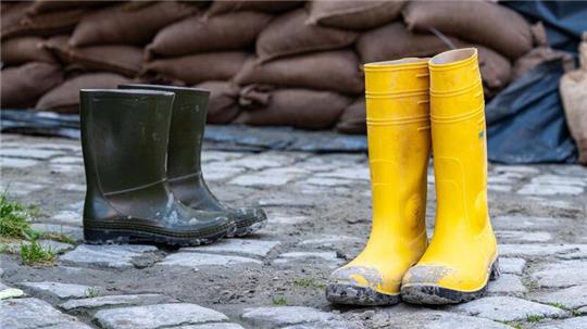 Gummistiefel stehen in der Altstadt vor Sandsäcken. Der Hochwassernachrichtendienst geht von einem baldigen Ende der Hochwasserlage in Bayern aus.