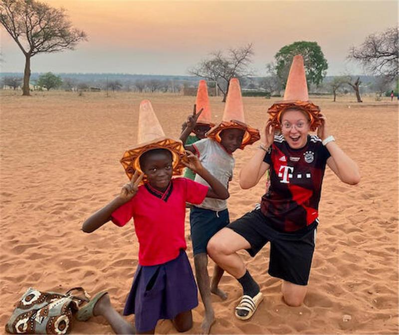 Amalia Saupe (19) aus Goslar trainiert ein Mädchenteam in Afrika Amalia Saupe setzt sich zusammen mit drei Kindern aus Mukuni ein Trainingshütchen auf den Kopf.