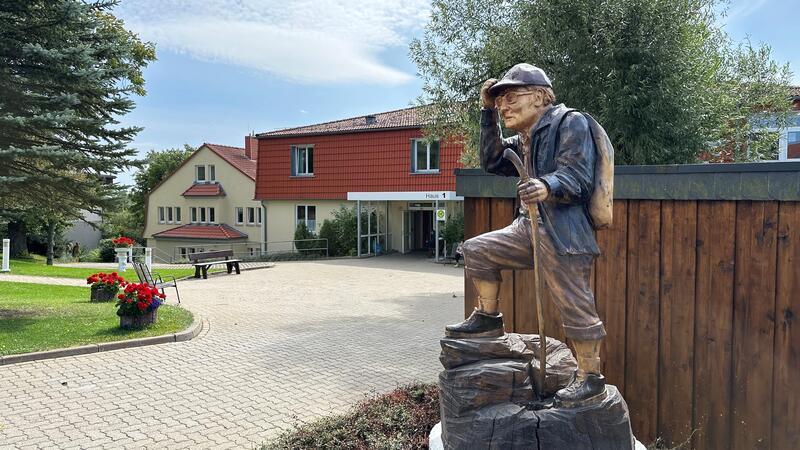 Familie unzufrieden mit Brocken-Benno-Skulptur aus Holz Gut sichtbar vor dem Alten- und Pflegeheim Bergresidenz steht jetzt die Holzschnitzerei, die offiziell „Der Wanderer" heißt.