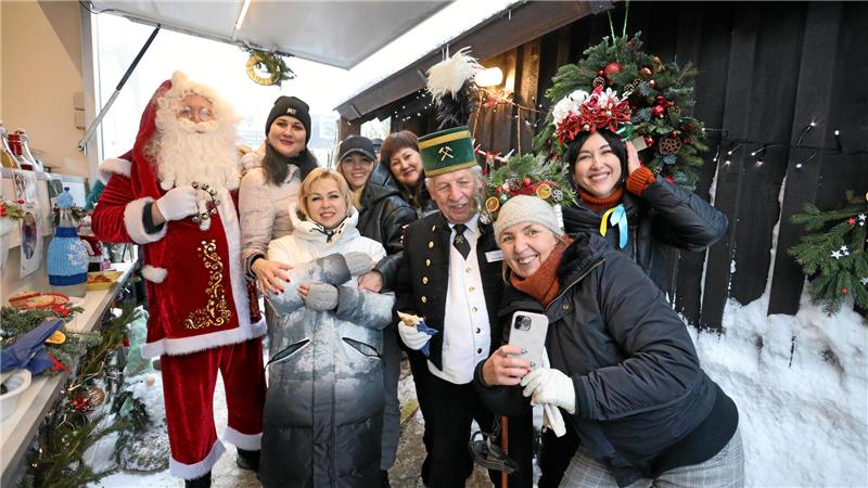Ein Mann ist als Weihnachtsmann verkleidet und steht neben diversen Frauen winterlich gekleidet sind.