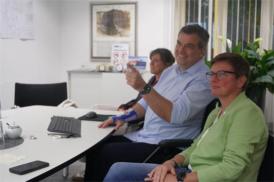 Drei Menschen sitzen nebeneinander.