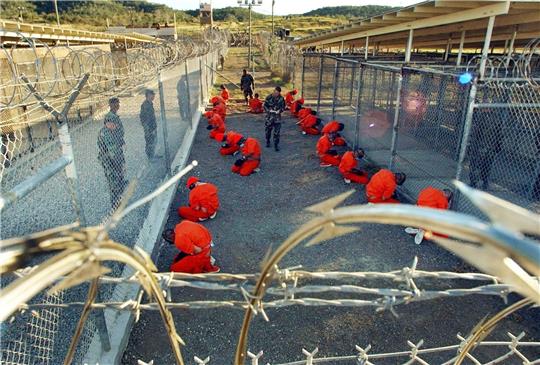 Häftlinge knien im Camp X-Ray des US-Marinestützpunkts Guantanamo Bay auf Kuba auf dem Boden.
