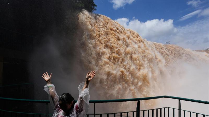 Hände hoch vor den Wassermassen der Iguazú-Wasserfälle in Brasilien