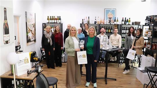 Gruppe von Menschen in einem Raum mit Weinflaschenregalen und Geschenktüten