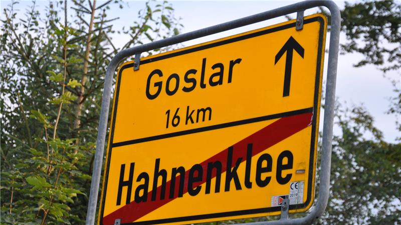 Gelbes Ortsschild mit durchgestrichenem Ortsnamen Hahnenklee und Pfeil mit Entfernungsangabe 16 km nach Goslar
