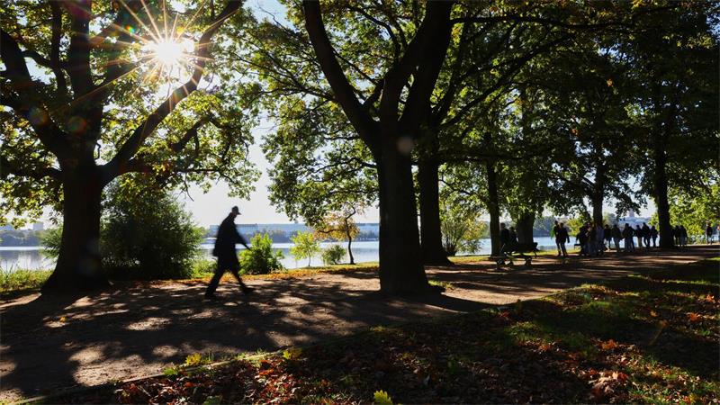 Hamburg: Bei Sonnenschein unterwegs – Menschen gehen an der Alster spazieren
