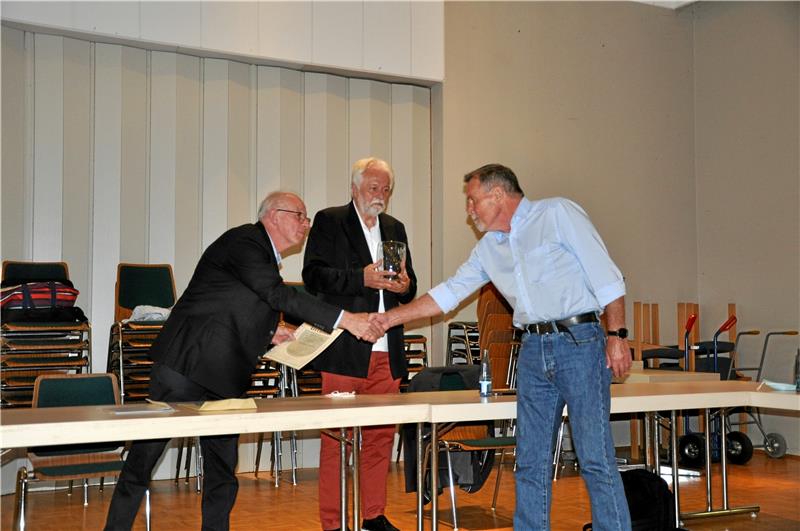 Hand drauf (v. li.): Ortsbürgermeister Heinrich Wilgenbus und Vize Professor Dr. Norbert Müller zeichnen Reinhold Eggers mit dem Ehrenpreis des Ortsrates aus.  Foto: Heine