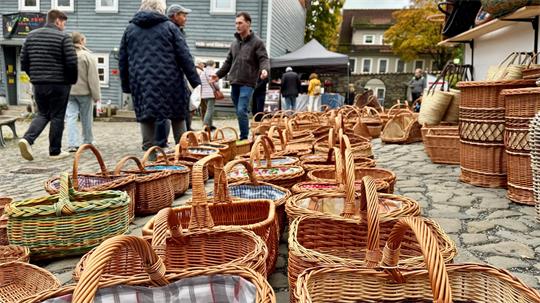 Mehrere geflochtene Körbe auf einem gepflasterten Platz mit Menschen im Hintergrund.