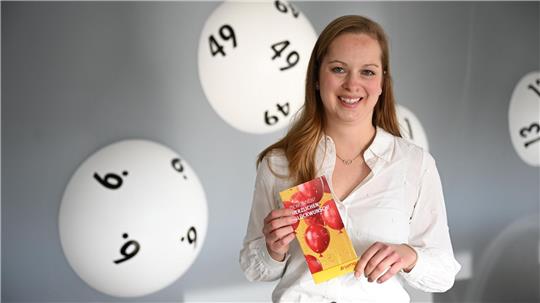 Hannah Strobel von Lotto Niedersachsen zeigt eine Broschüre für Lottogewinner.