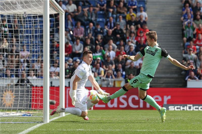 Hannover 96 atmet auf: „Enorm wichtiger Sieg” in Bielefeld Hannovers Fabian Kunze (r) schießt vorbei an Bielefelds Torwart Martin Fraisl ins Tor.
