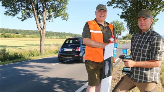 Hans Hesse (l.), Pächter des Jagdreviers Heißum, und der Jäger Andreas Teuber bringen am Dienstag einen Teil der neuen Wildwarnreflektorten an.