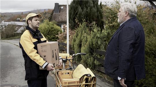 Zwei Männer stehen auf einer Straße und sprechen miteinander.