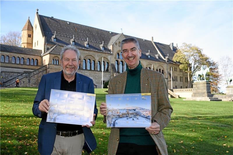 Goslarer Spendenaktion: Kein Kind soll kalte Füße kriegen Hartmut Prüssner und Michael Mayr (v.li.) stellen den neuen Adventskalender des Lions Clubs Goslar-Rammelsberg vor: Auf dem Kalender die Kaiserpfalz im Schnee, hinter den Lions die Kaiserpfalz im Herbstlicht. Foto: Kempfer