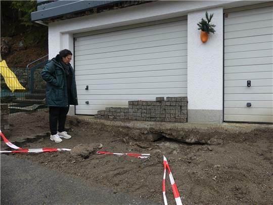 Hauseigentümerin Berna Acar-Grothe vor der Garage, unter der das Loch aufgetaucht ist. An der Hausecke ist das Loch ersten Messungen zufolge mindestens sechzig Zentimeter tief (kl. Bild).  Fotos: Römhild