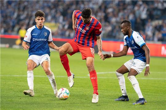 Heidenheims Tim Kleindienst (M) im Ballbesitz wird von den Magdeburgern Silas Gnaka (r) und Daniel Elfadli bedrängt.