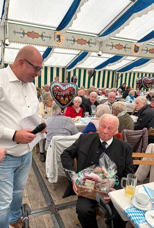 Heinrich Burhenne ist mit 94 Jahren einer der ältesten Besucher und bekommt vom Ortsbürgermeister Rene Philipp ein Präsent überreicht.