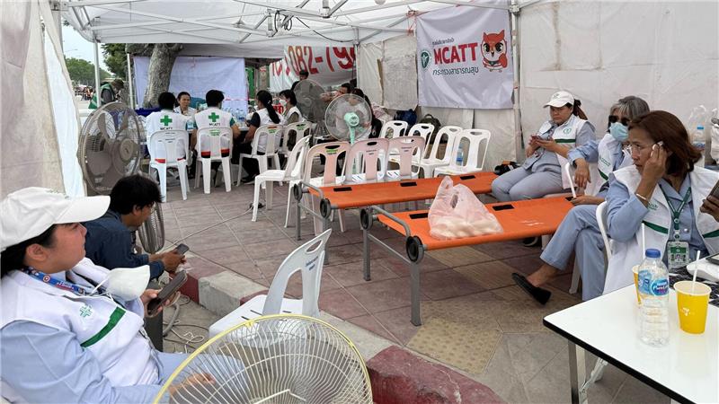 Verzweifelte Suche nach Lebenszeichen in Bangkok Helfer ruhen sich im Schatten von den Strapazen und der Hitze aus und haben einen Ventilator im Erste-Hilfe-Zelt angestellt.