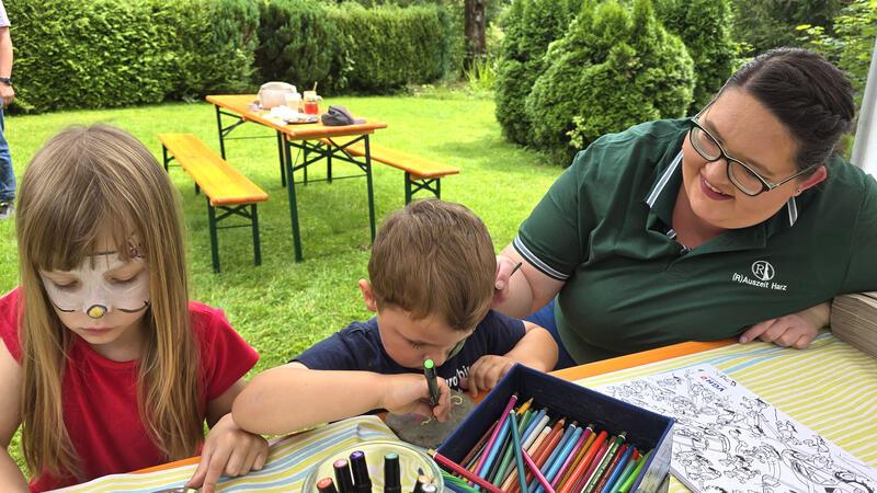 Sommerfest in Wildemann: Tombola-Lose unterstützen Spiegelbad Helferin Vivien (r.) hat ihre Schminkarbeit gerade erledigt und beobachtet, wie Melina und Laif daraufhin einige Steine bemalen.