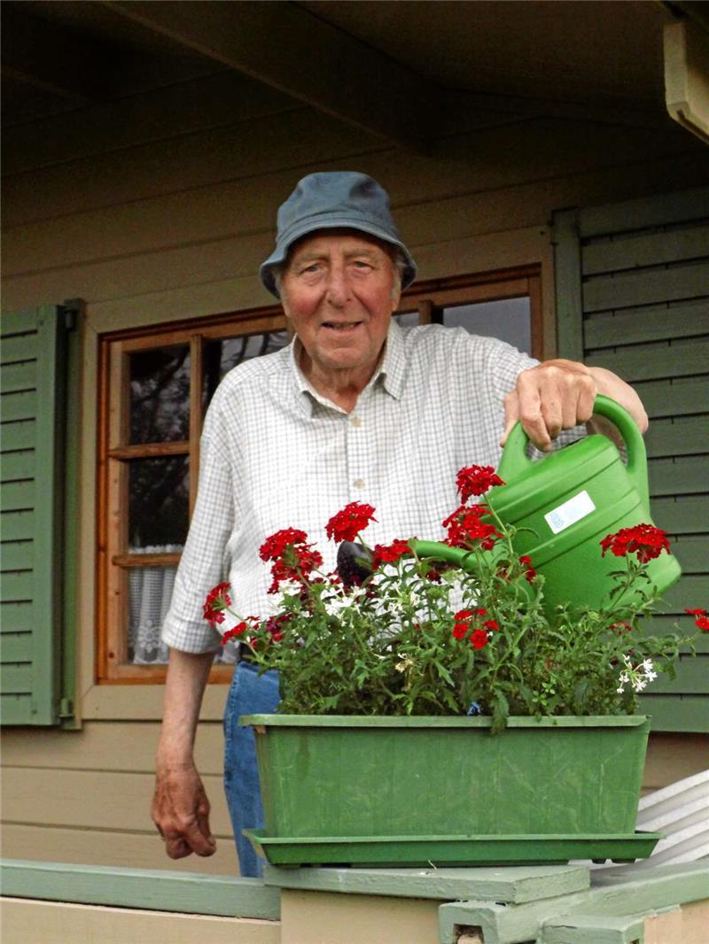 Herbert Hemler gießt die Geranien auf der Laubenterrasse.