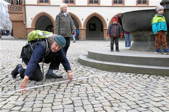 Hier könnte ein Granit- oder Sandsteinring entstehen, damit Rollstuhlfahrer problemlos zum Brunnen gelangen: Behindertenbeauftragter Axel Dietsch fordert Barrierefreiheit auch auf dem Goslarer Marktplatz und nimmt schon mal Maß für die dafür nötigen Bauarbeiten. Foto: Hartmann