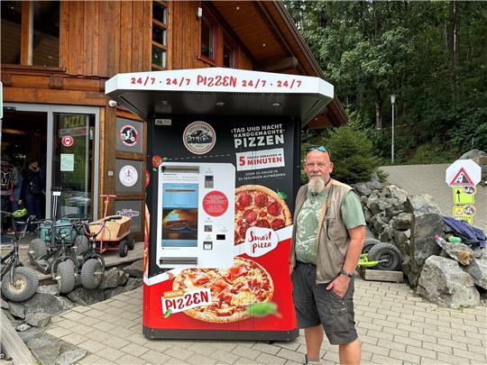 Hinrich Bothe vor seinem Pizza-Automaten, der bereits kräftig genutzt wird. Rund um die Uhr holen die Kunden (kleines Bild) die Pizzen ab, die über ein Fach herausgegeben werden. Foto: Eggers