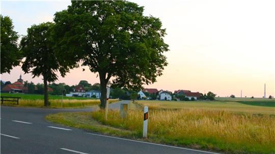 Hinter der Ortschaft wächst (rechts im Hintergrund) weithin sichtbar der Windpark in die Höhe.