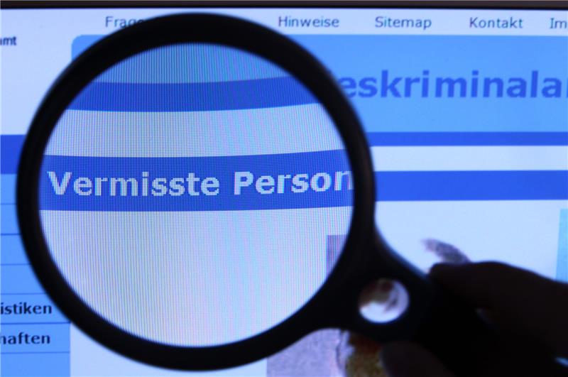 Hinter einer Lupe ist der Schriftzug "Vermisste Person" auf einem Fahndungsaufruf auf der Internetseite des Bundeskriminalamtes (BKA) zu sehen. Foto: picture alliance/dpa/dpa-Zentralbild | Jens Büttner