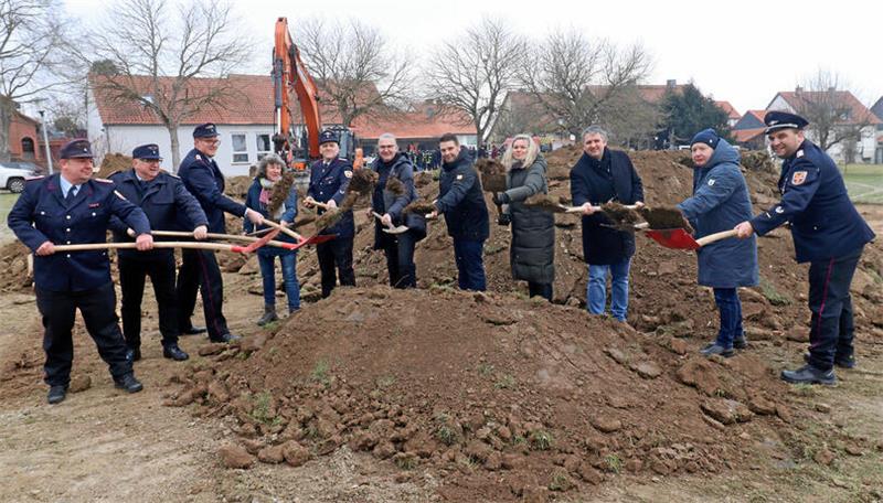 Personen mit Spaten und Schaufeln stehen an einem Erdhaufen.